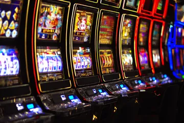 A woman smiling by bright slot machines showing lucky symbols, showcasing the exciting slot offerings at GB44.
